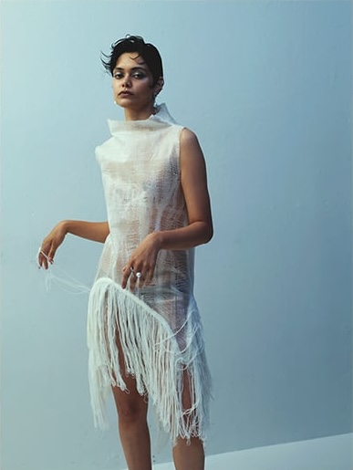 Model Zinnia Kumar wearing a white sheer fringe dress against a light blue studio background for Russh editorial photography.