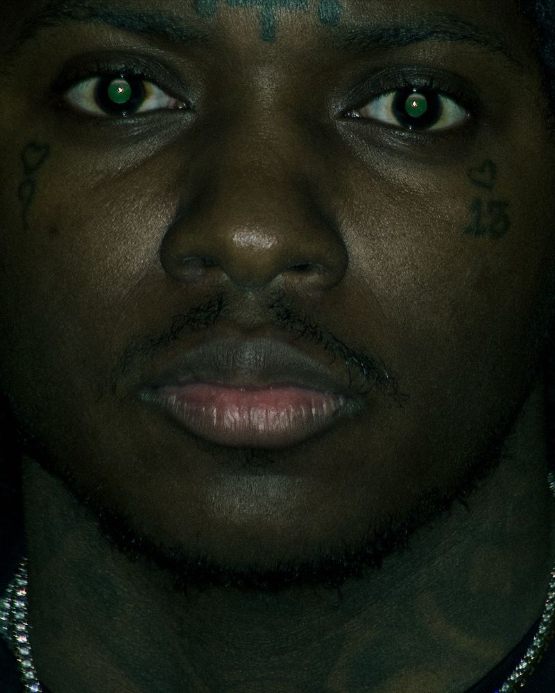 Close-up portrait of a Black man with facial tattoos and green contact lenses for Nike Jumpman by Cactus Jack.
