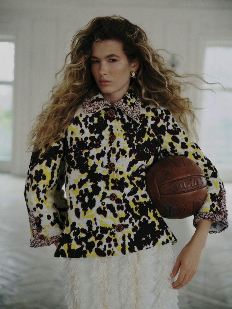 Model Meg Dmitruk wearing a patterned jacket holding a leather ball for Elle Poland Prêt-à-sporter