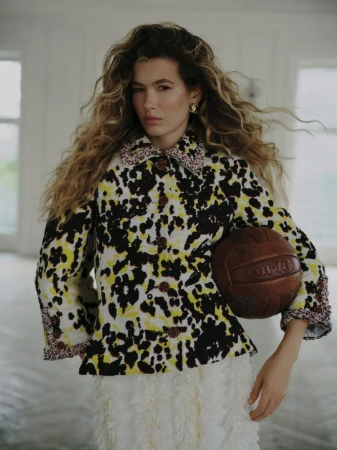 Model Meg Dmitruk wearing a patterned jacket holding a leather ball for Elle Poland Prêt-à-sporter