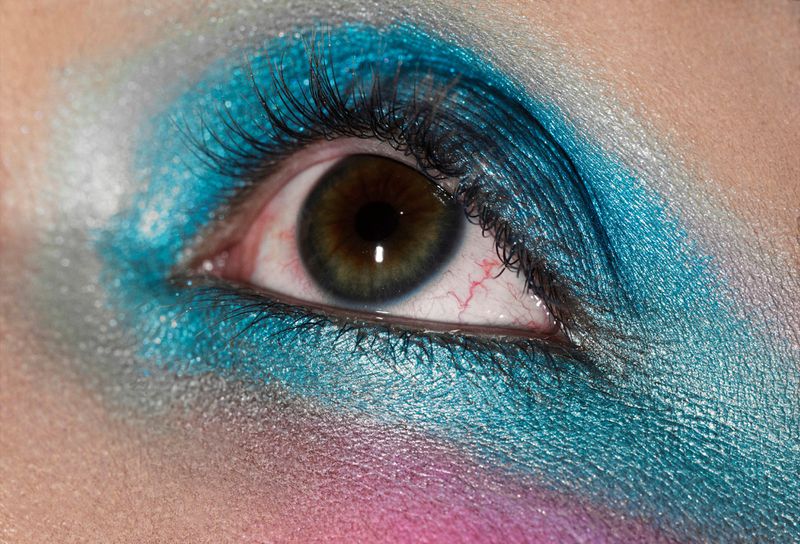 Close-up of a human eye adorned with vibrant blue eyeshadow and dark eyelashes for Beyond Noise editorial photography.