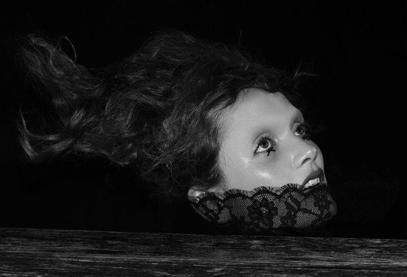 Model Gertrud Rose in black lace and dark makeup against a black backdrop for Beyond Noise by photographer Willy Vanderperre.