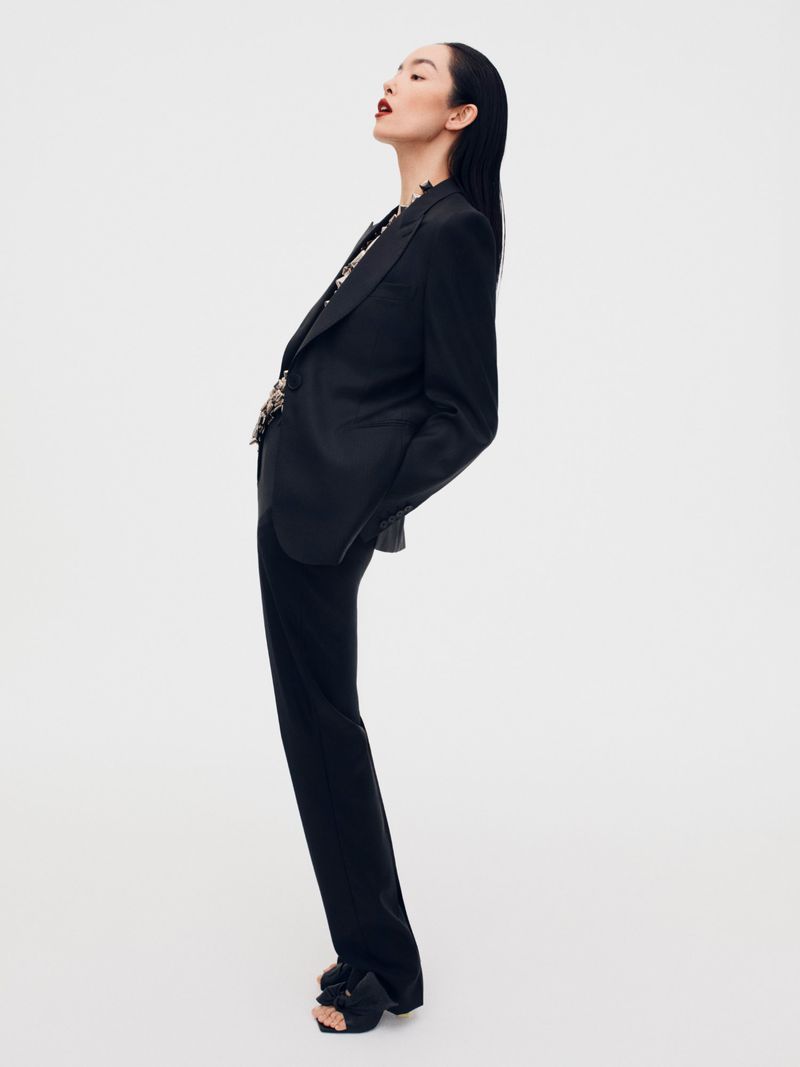 Model FeiFei Sun wearing a black blazer and trousers against a white seamless background for Beyond Noise