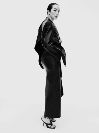 Model FeiFei Sun wearing a black leather coat against a white seamless studio background for Beyond Noise