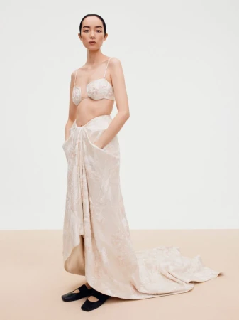 Model FeiFei Sun wearing a cream patterned bra top and long skirt in a studio setting for Beyond Noise