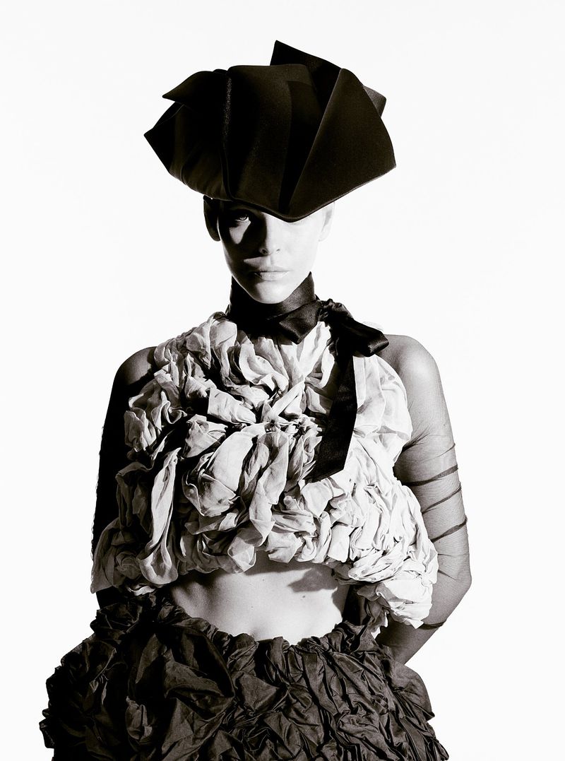 Model Vittoria Ceretti wearing an avant-garde black hat and sculptural textured top against a white seamless background