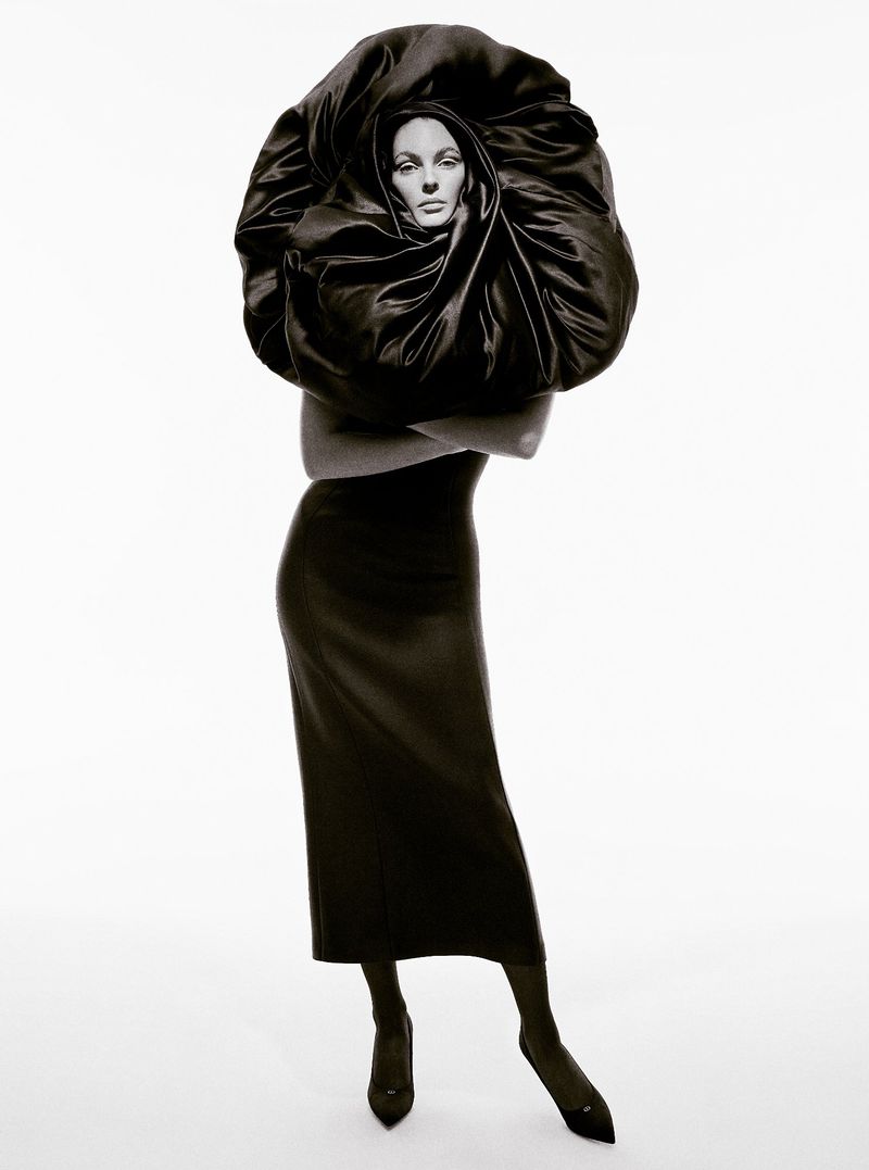 Vittoria Ceretti wearing a sculptural black ruffled headpiece and dark dress against a white background for Beyond Noise