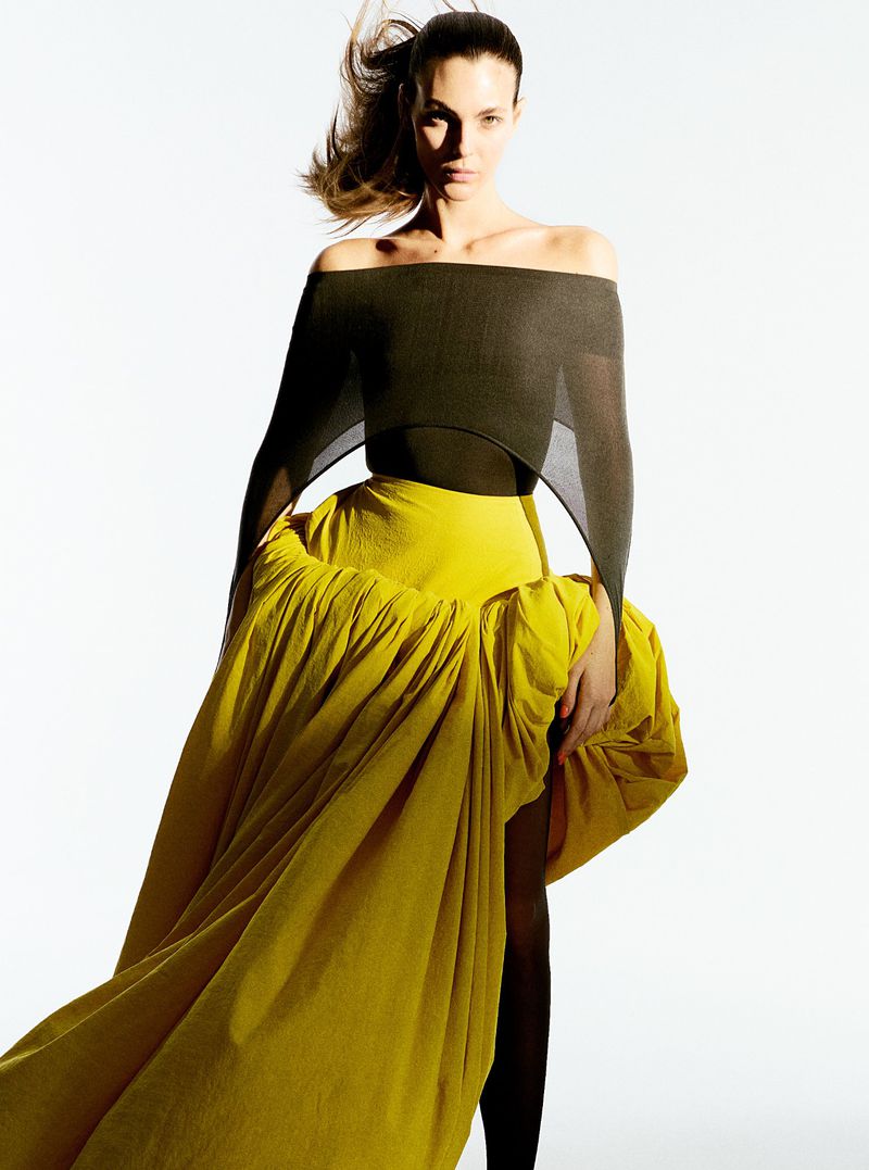 Model Vittoria Ceretti wearing an off-the-shoulder dark top and voluminous yellow skirt against white background