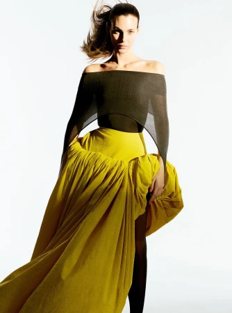 Model Vittoria Ceretti wearing an off-the-shoulder dark top and voluminous yellow skirt against white background