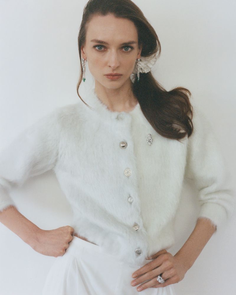 Model in white fluffy cardigan and silver earrings posing against a plain background for Numéro Istanbul