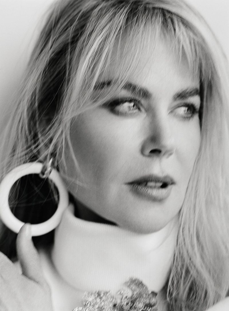 Monochrome portrait of an adult female with blonde hair, wearing large hoop earrings, looking off to the side against a neutral background.