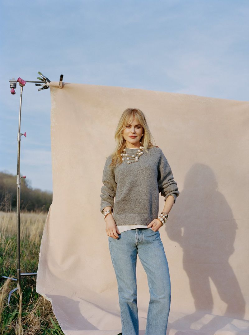 Nicole Kidman wearing a grey sweater and blue jeans posing in front of an outdoor photography backdrop for Vogue China.