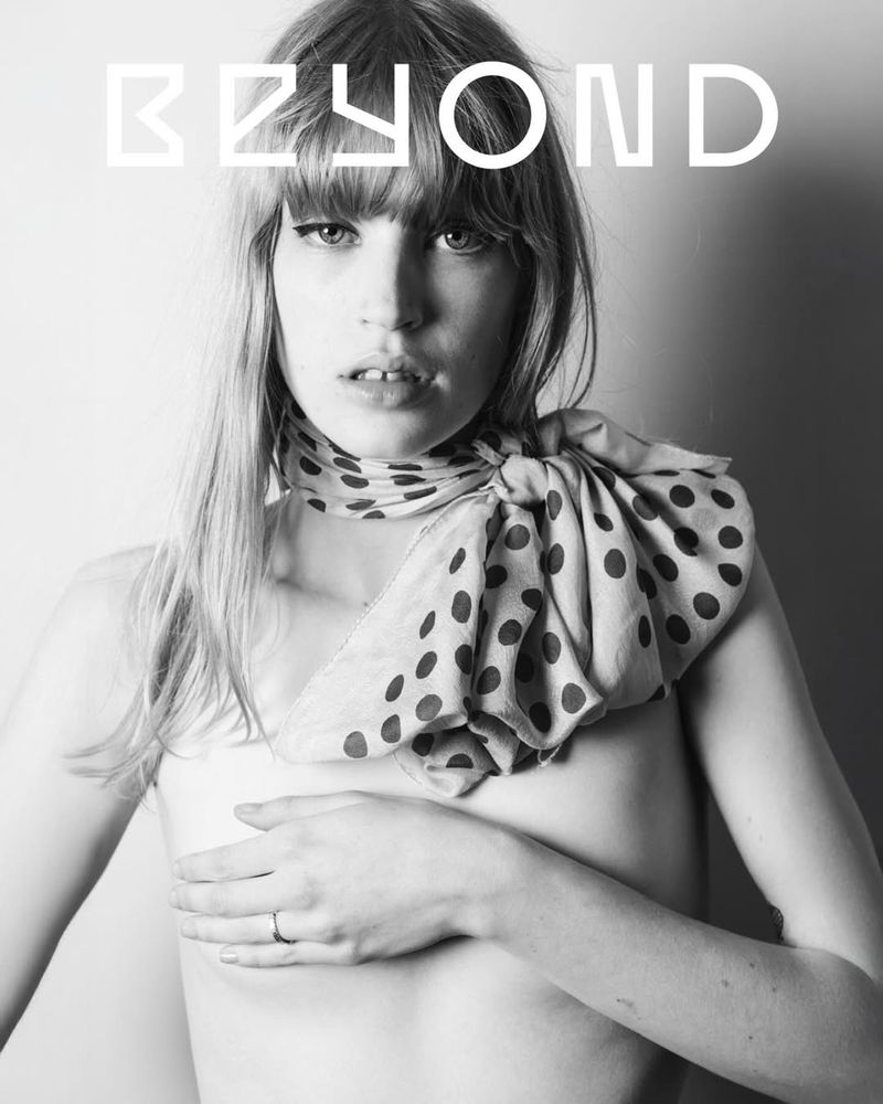 Black and white fashion portrait of a young adult woman with a polka dot scarf covering her chest, showcasing her bare skin.