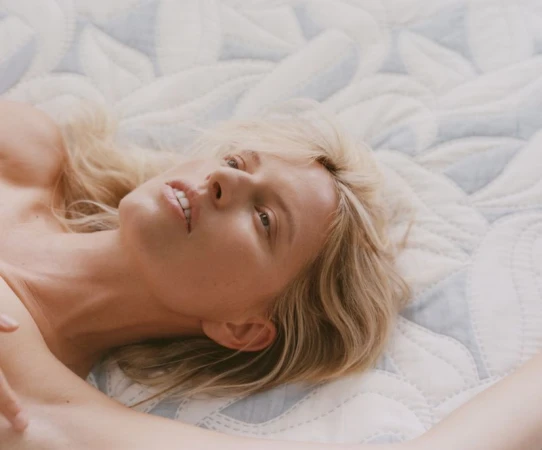Close-up portrait of blonde model Karolina Kurkova reclining on a patterned quilted textile background for Vogue Czechoslovakia.