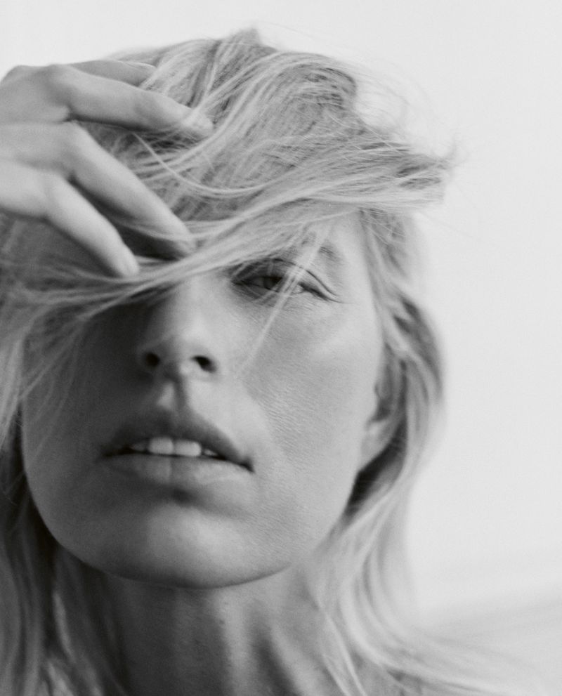 Close-up portrait of model Karolina Kurkova with blonde hair across her face against a plain background