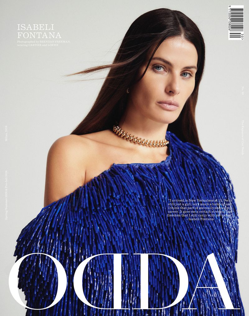 Isabeli Fontana wearing a blue textured top and gold choker necklace against a white background for ODDA Magazine April 2026