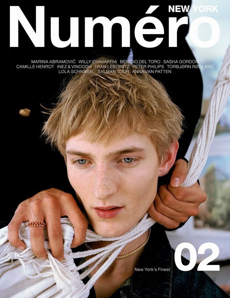 Close-up portrait of a young male model with blonde hair holding thick white rope for Numero New York magazine.