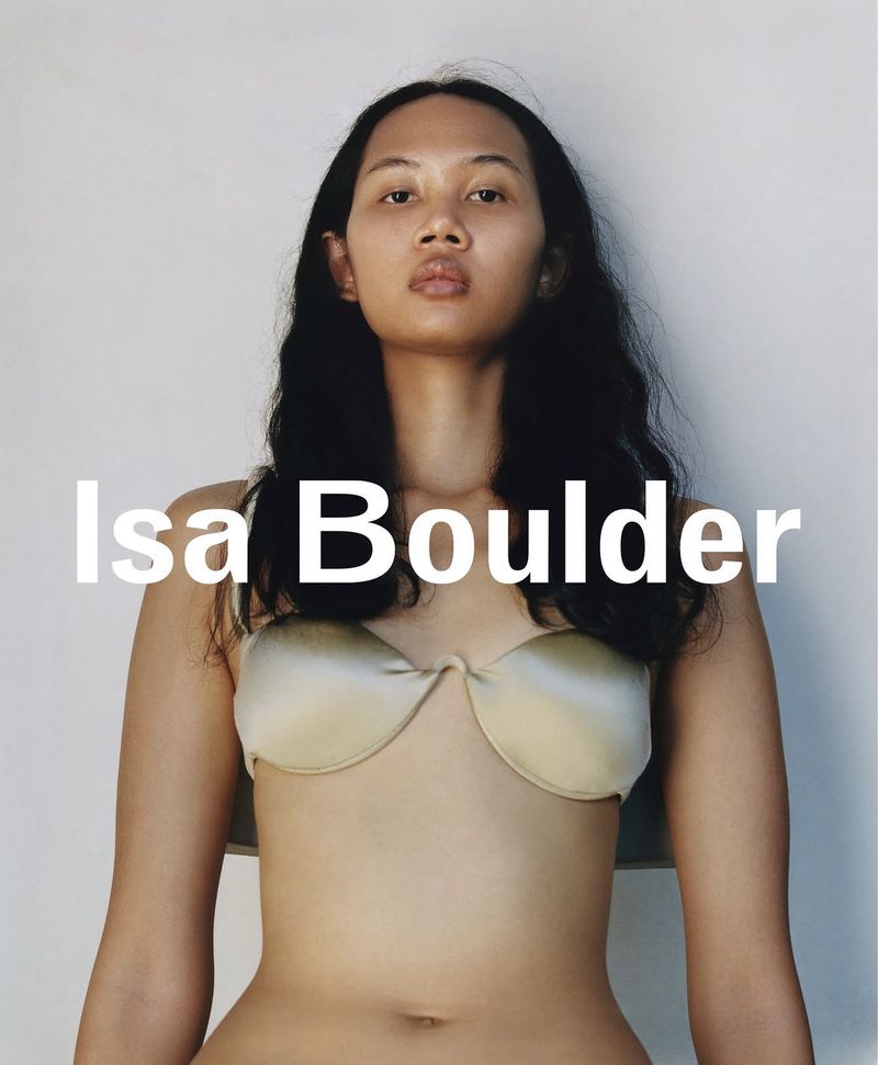 Model wearing a metallic satin bra top against a white seamless background with overlaid text