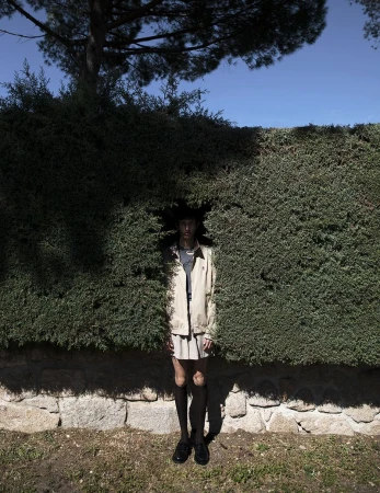 Model Nicolas Secades standing in an opening of a tall green hedge for L'Officiel Hommes Malaysia photographed by Karl Simone.