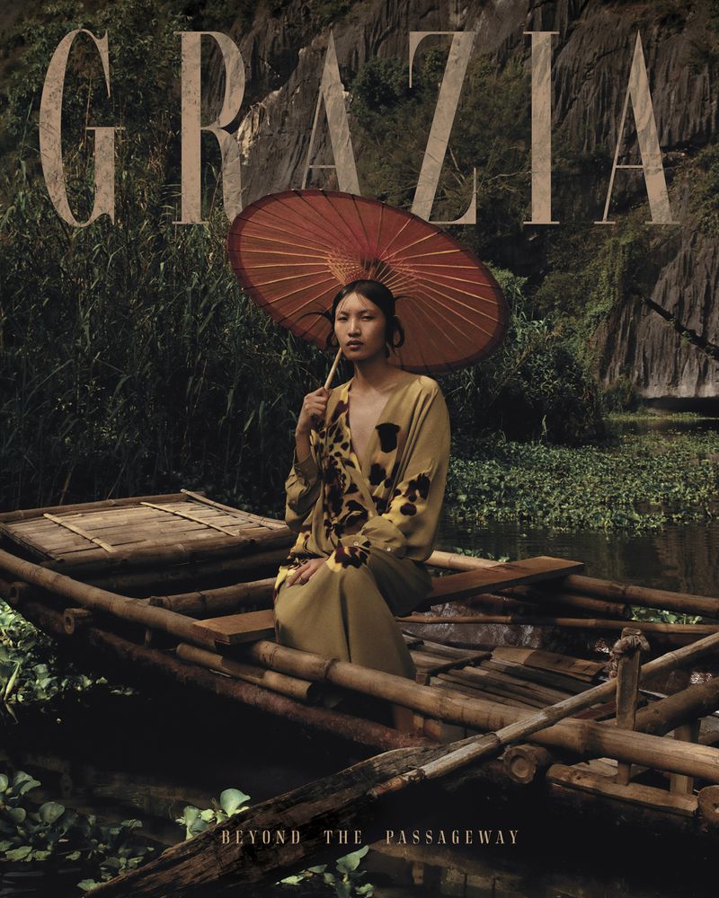 Fashion editorial portrait of an Asian woman in a boat, holding an umbrella, surrounded by green plants, with 'Grazia' text overlay.