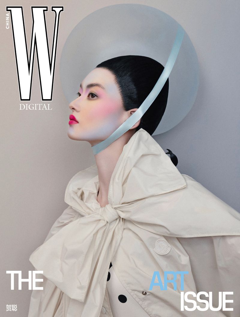 Elegant magazine cover featuring an Asian woman with vibrant makeup, wearing a large bow and halo against a muted grey backdrop.