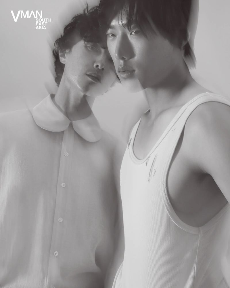 Two young Asian men pose in a B&W studio shot, one in a white tank top and the other in a dress shirt, captured in soft focus.