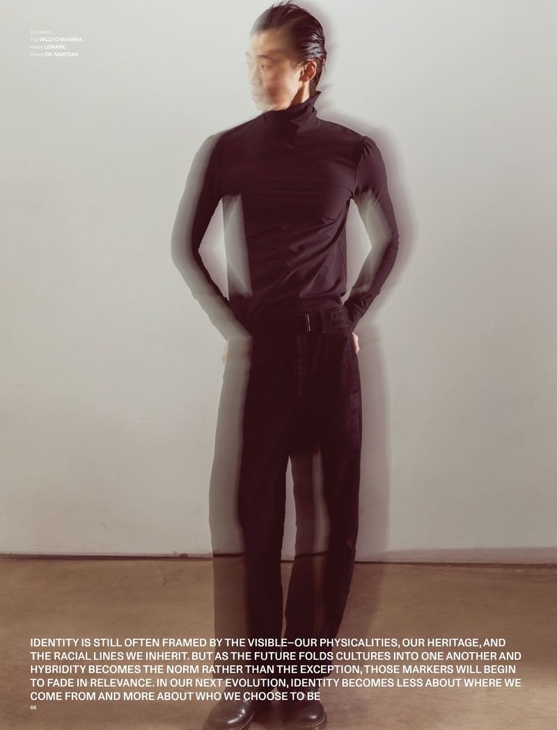 Model in black turtleneck and dark trousers standing against a plain background with motion blur ghosting effects.