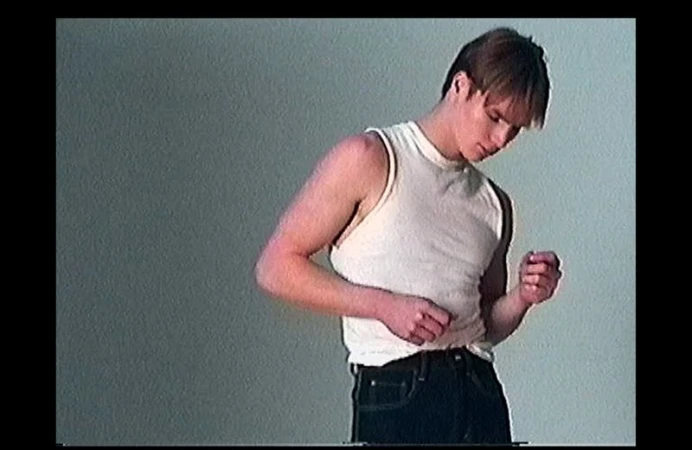 Model Henry Rank in a white tank top and dark jeans against a grey seamless background photographed by Fabien Kruszelnicki.