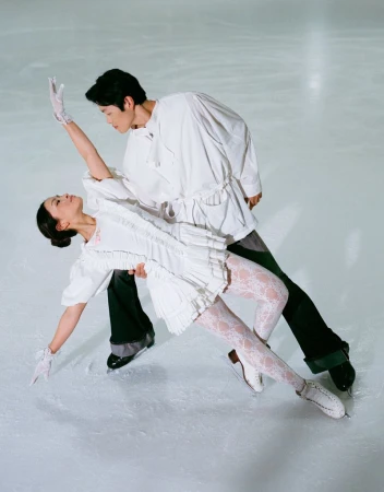 Figure skaters Alex and Maia Shibutani performing on ice in matching white outfits for HERO USA.