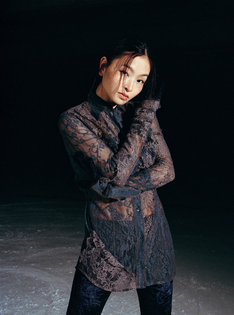 Portrait of Maia Shibutani wearing a sheer dark lace long-sleeve top against a dark moody background shot by Daria Kobayashi Ritch.