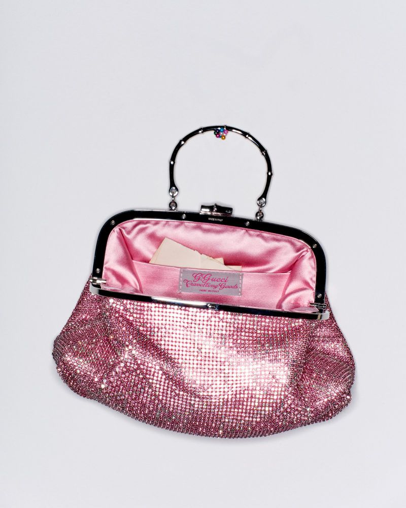 Sparkling pink rhinestone evening handbag with a metal frame and handle open against a plain white background.