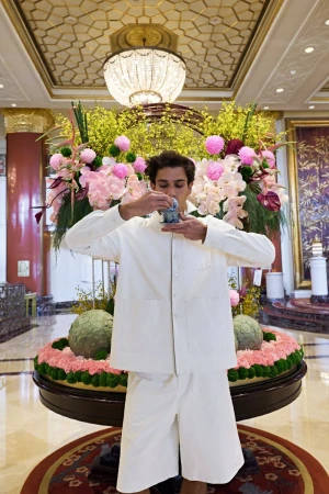 Model in white shirt and shorts holding teacup in luxury hotel lobby for GQ China