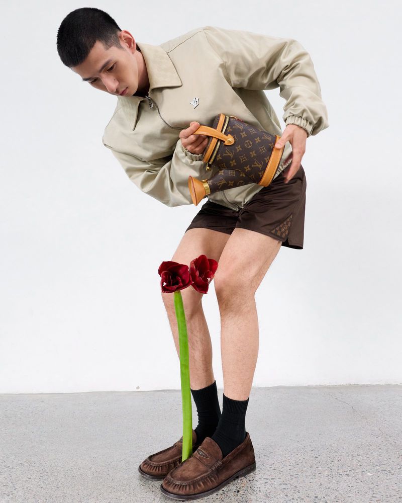 Model pouring water from a monogrammed watering can onto a red flower for GQ China, styled by Jiacheng Wu and photographed by Shenyun Ren.