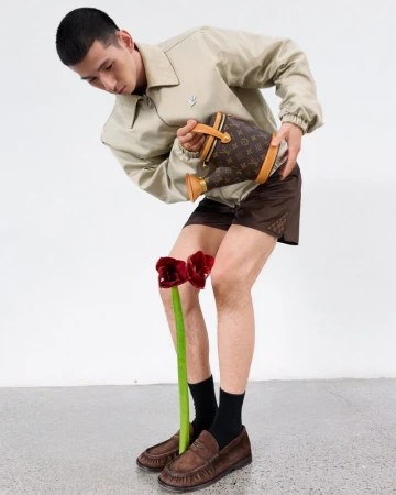 Model pouring water from a monogrammed watering can onto a red flower for GQ China, styled by Jiacheng Wu and photographed by Shenyun Ren.