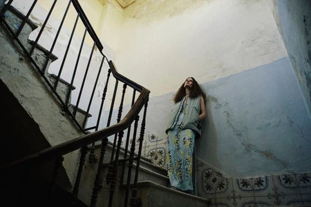 Model standing on a staircase leaning against a weathered wall for The Collector Magazine editorial