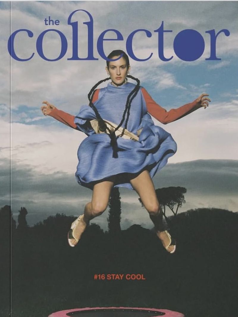 Model jumping in air against cloudy sky wearing blue dress and orange sleeves for The Collector Magazine spring issue