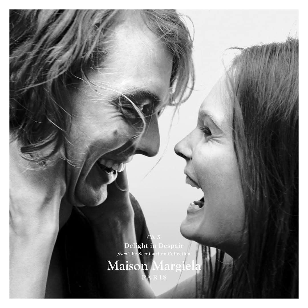 Black and white portrait of a laughing man and woman facing each other with text overlay from Maison Margiela