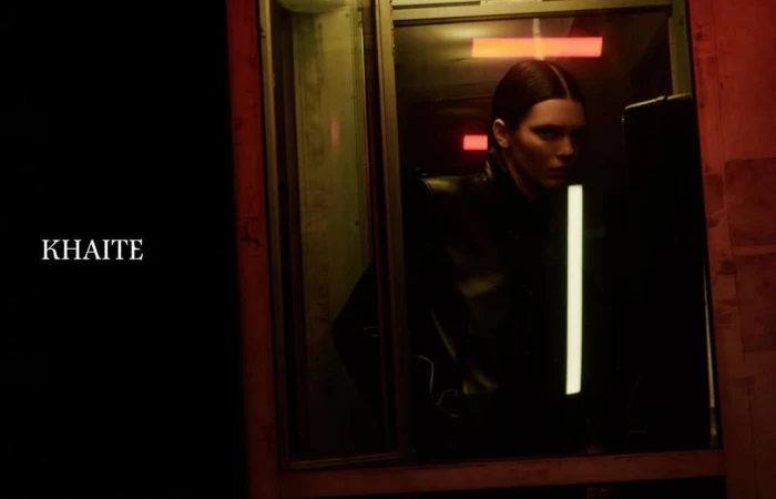 Kendall Jenner in a dark leather jacket looking through a window for the Khaite Spring 2026 ad campaign photographed by Drew Vickers