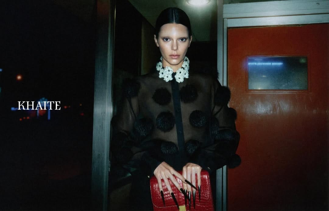Kendall Jenner in a black sheer dotted shirt holding a red handbag for Khaite spring 2026 ad campaign