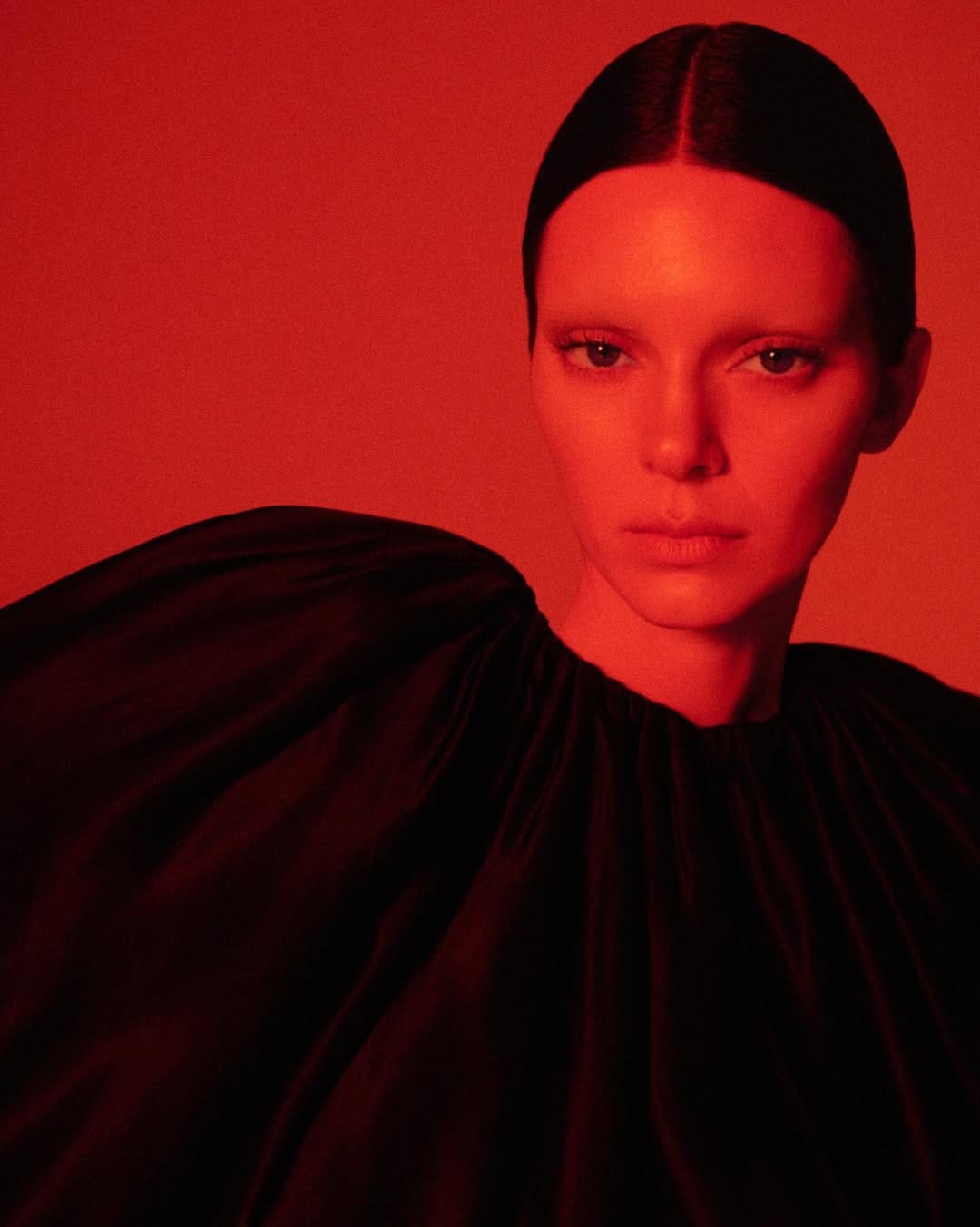 Kendall Jenner in a dark pleated top bathed in red light for Khaite Spring 2026 ad campaign shot by Drew Vickers.