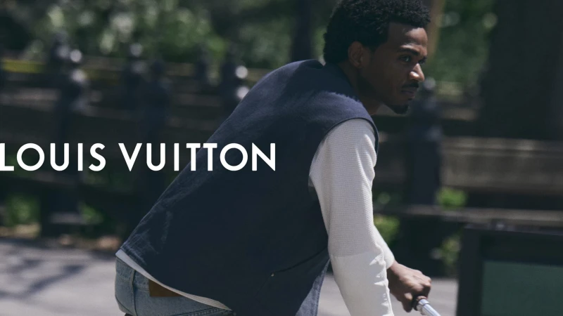Tyshawn Jones riding a bicycle in Central Park wearing a dark vest and white shirt for Louis Vuitton.