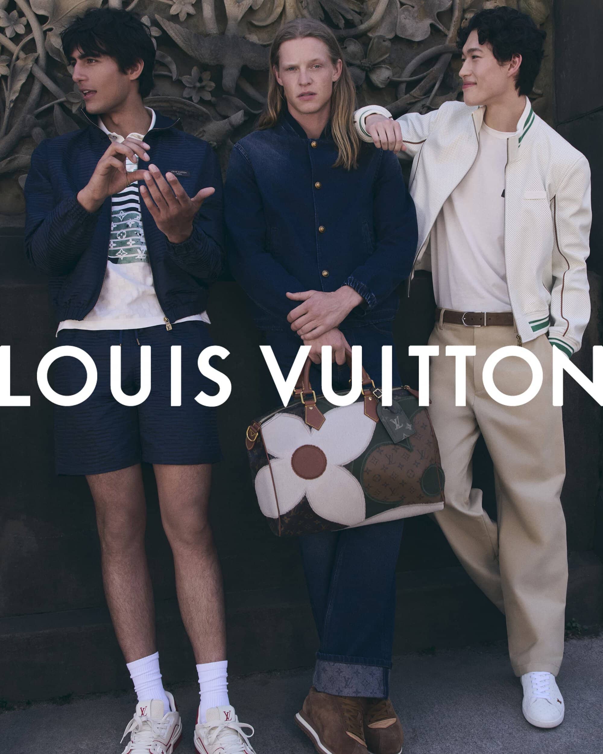 Three male models posing together outdoors against a stone wall for the Louis Vuitton Pre-Fall 2026 men's campaign.
