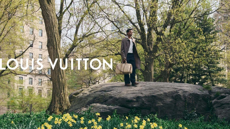 Tyshawn Jones standing on a large rock in Central Park carrying a Louis Vuitton travel bag for the Pre-Fall 2026 campaign.