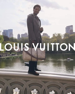 Tyshawn Jones standing on a stone bridge holding a monogram duffel bag for the Louis Vuitton Pre-Fall 2026 Men's Campaign.