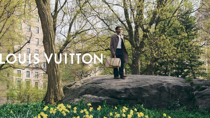 Tyshawn Jones standing on a large rock in Central Park carrying a Louis Vuitton travel bag for the Pre-Fall 2026 campaign.