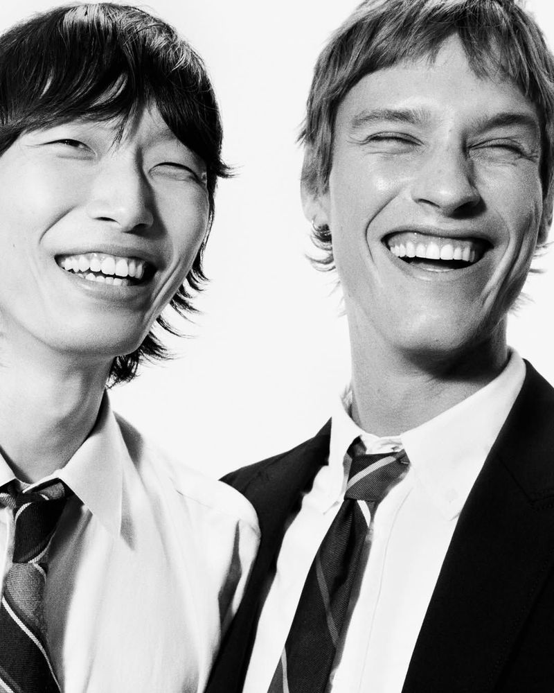 Two smiling male models wearing white shirts and ties against a bright white background for Mr Porter