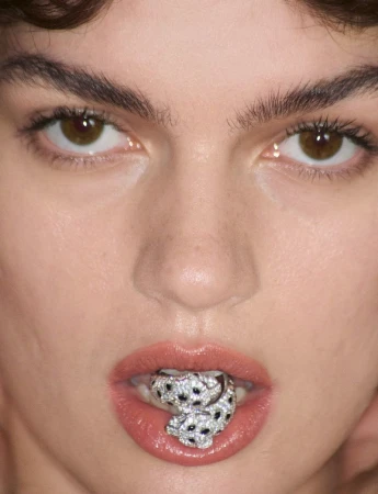Extreme close-up portrait of a model holding a diamond-encrusted panther ring between her lips
