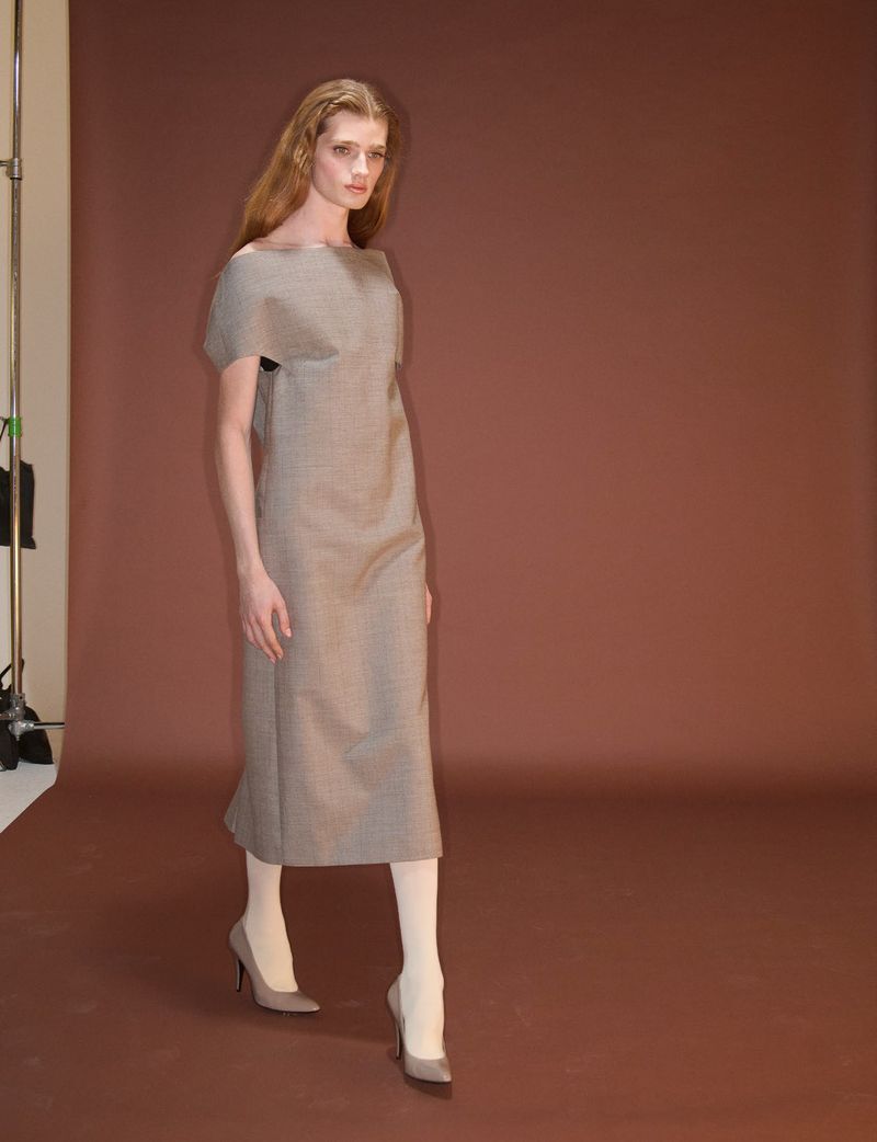 Model in brown midi dress and heels walking against a brown backdrop for System Collections Autumn Winter 2026-2027.