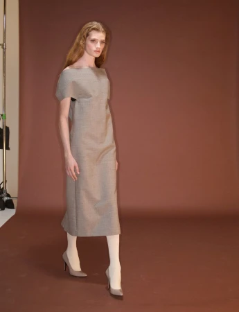 Model in brown midi dress and heels walking against a brown backdrop for System Collections Autumn Winter 2026-2027.