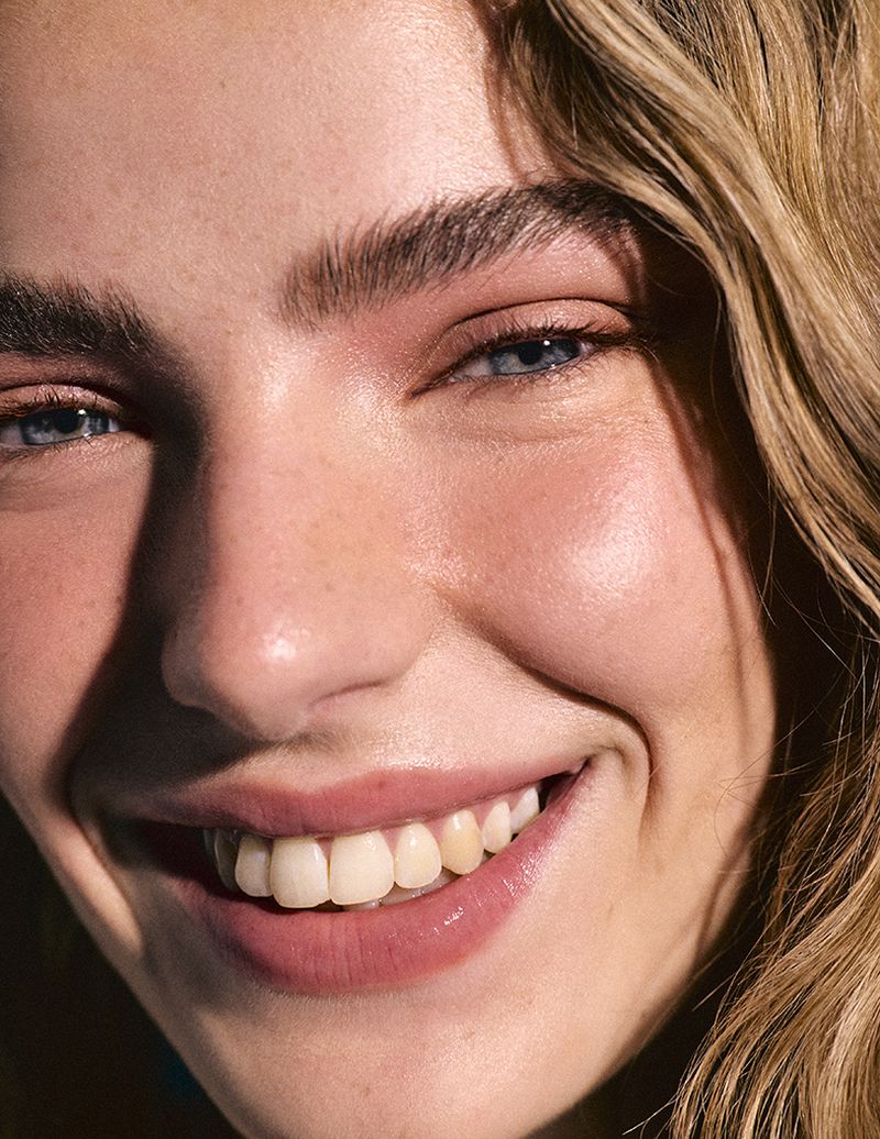 Close-up portrait of a smiling woman with blue eyes and blonde hair for Harper's Bazaar España Sunny Pills editorial.